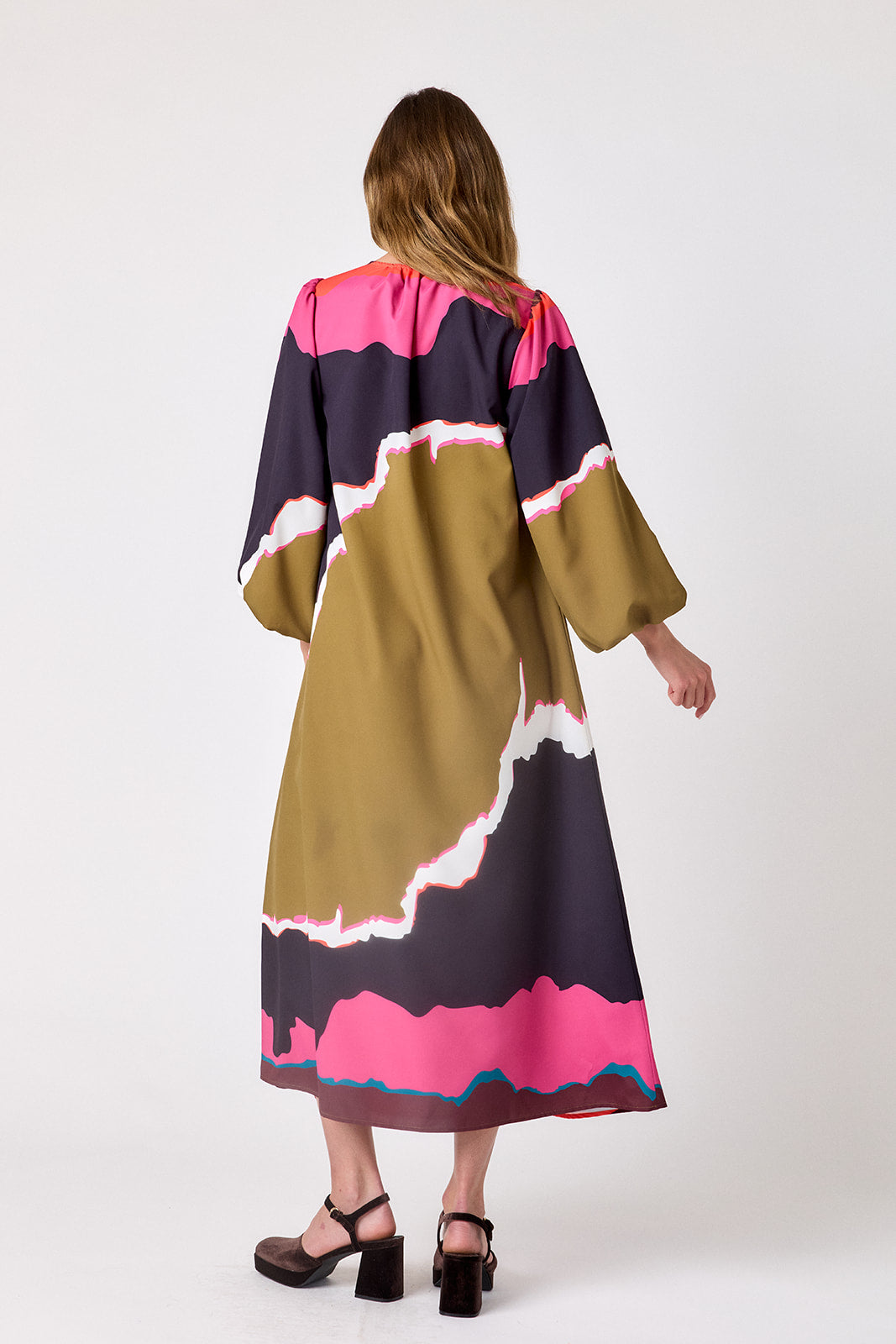 Crosby Ryker Dress in Portoro, back view on model showing trapeze silhouette, full sleeves gathered at the wrist, and pink and teal print bands at the hem