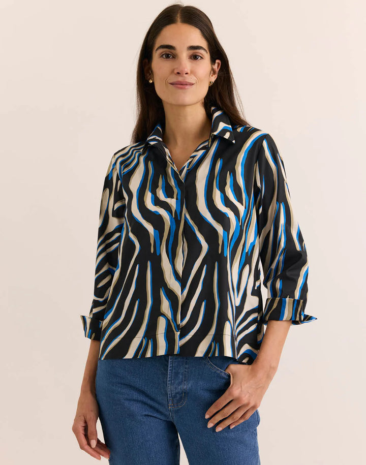 Hinson Wu 3/4 Sleeve Xena Top in abstract zebra print of black, cobalt blue, and sand, styled with a point collar and cuffed sleeves, worn with medium-wash denim against a neutral backdrop.