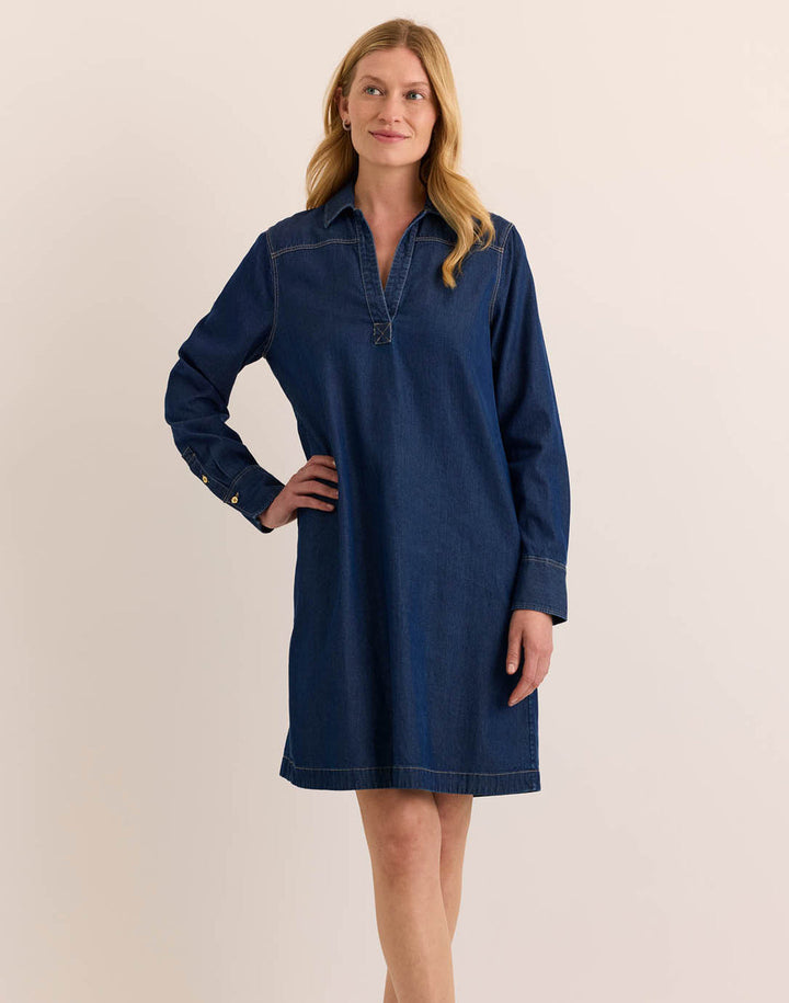 Woman wearing a blue denim dress against a beige background