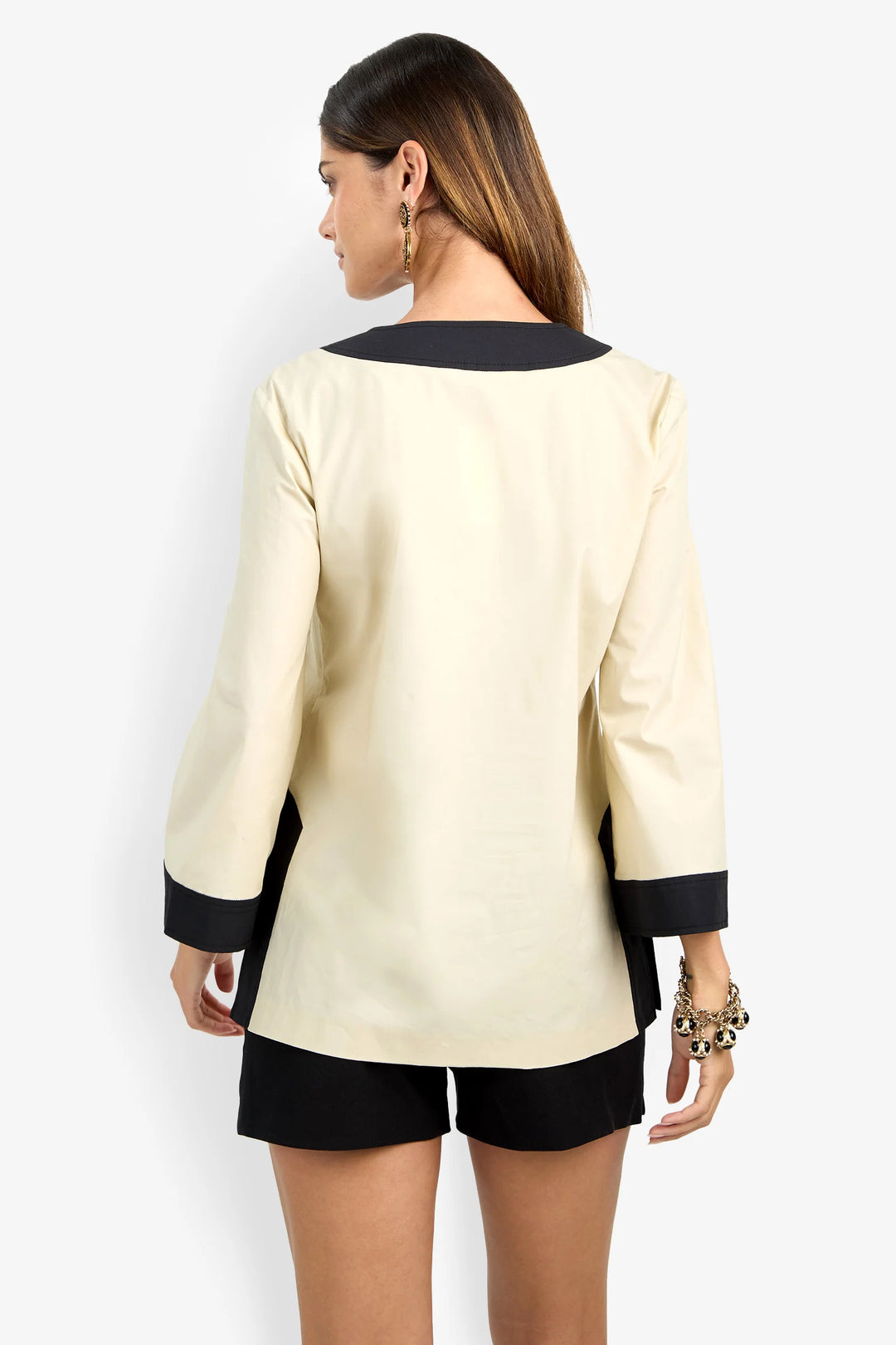 Trina Turk Dametria Top in ivory and black colorblock, back view, showing contrast neckline binding, cuffs, and side slit.