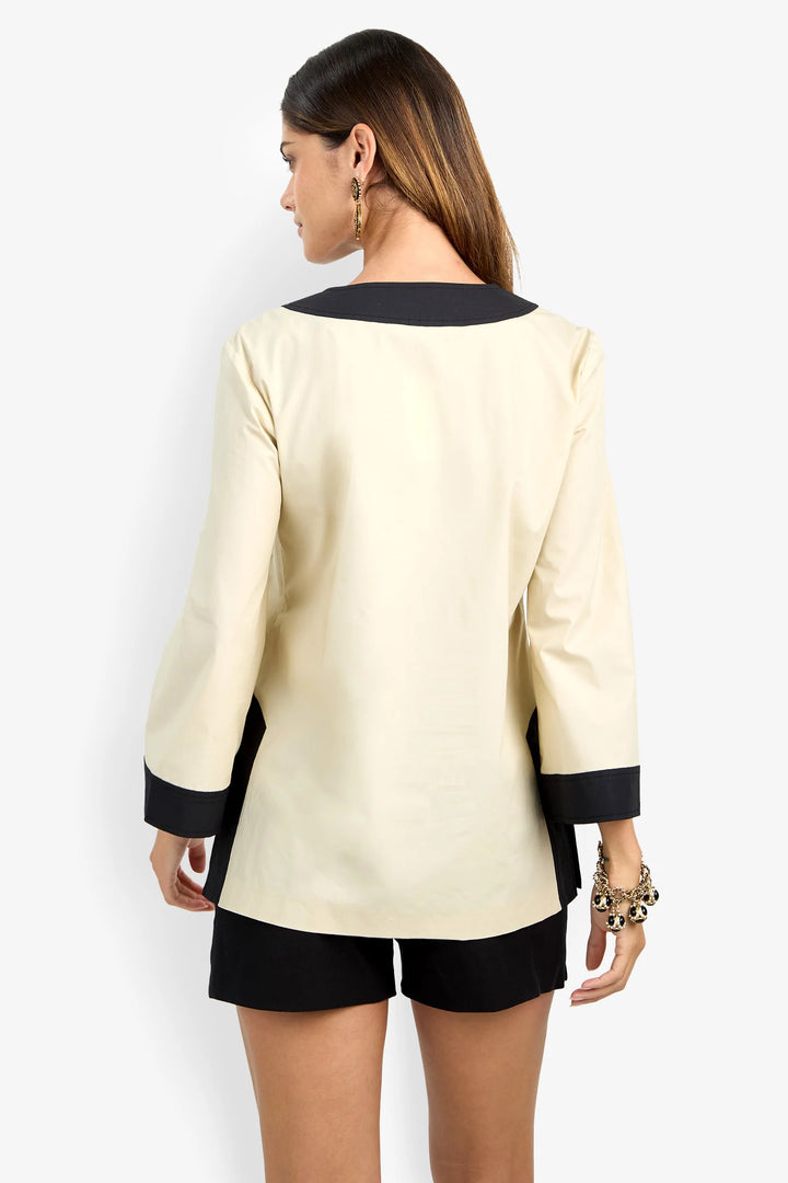 Trina Turk Dametria Top in ivory and black colorblock, back view, showing contrast neckline binding, cuffs, and side slit.