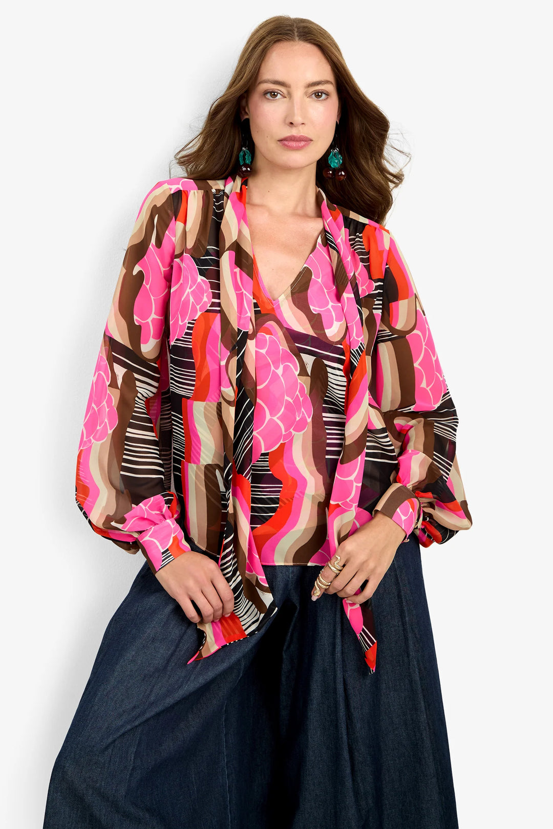Trina Turk Pienza Top in pink, brown, and orange abstract print, close front view, V-neckline with tie detail and balloon sleeves.