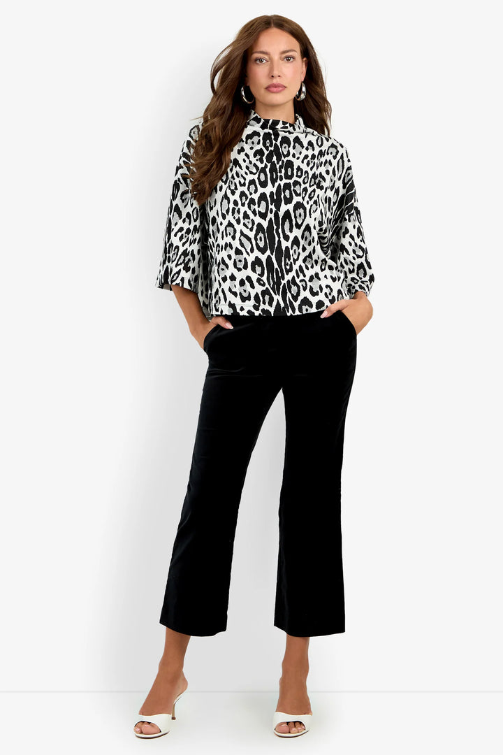 Model wearing the Trina Turk Sidony Top in black-and-white leopard print with a funnel neck, elbow-length dolman sleeves, and cropped black trousers.