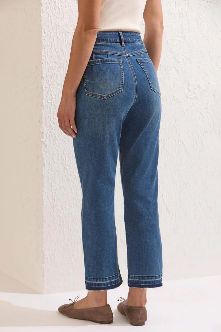 Full-body back view of a model wearing the jeans, showing the curvy fit through the seat and thigh and the raw released hem at the ankle.