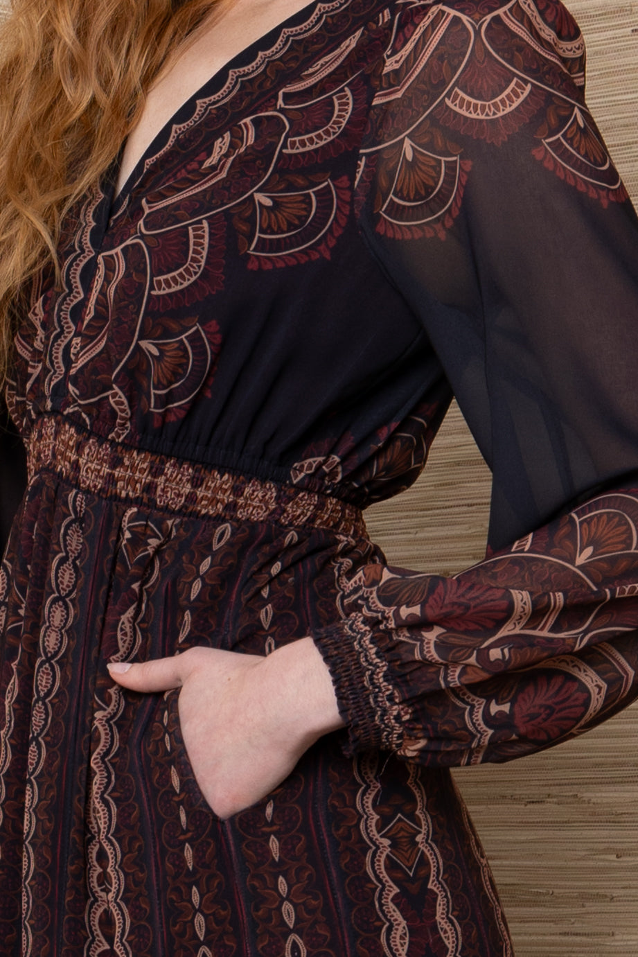 Hale Bob Iselda V Neck Maxi in Plum Multi, close-up of the bodice showing scalloped print along the V-neckline, smocked waistband, side-seam pocket, and sheer sleeve with smocked cuff.
