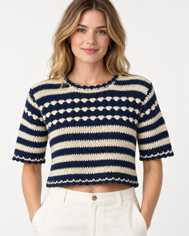 Front view of a model wearing the crop crochet sweater, showing the striped pattern, scalloped neckline, and shell-stitch detailing across the chest.