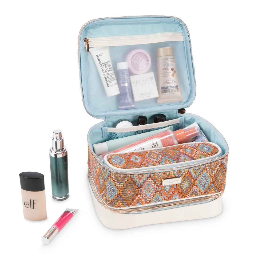 Open/styled view: Stephanie Johnson Jenny Train Case open and packed with skincare and makeup products, showing pale blue interior lining, mesh organization pockets, and removable zippered pouch in matching Bodrum Kilim print.