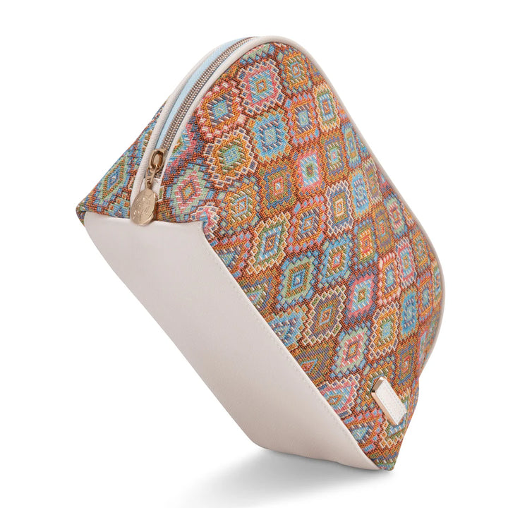 Side/end view: Stephanie Johnson Lola Makeup Bag in Bodrum Kilim print, showing triangular end profile, center zipper with ivory trim, and rose gold zipper pull with engraved medallion.