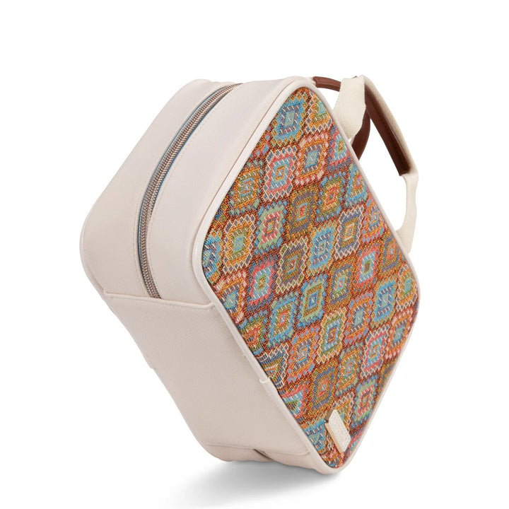Three-quarter view with badge: Stephanie Johnson ML Traveler in Bodrum Kilim print, angled to show woven panel and ivory faux-leather trim, with recycled materials badge in upper left corner.