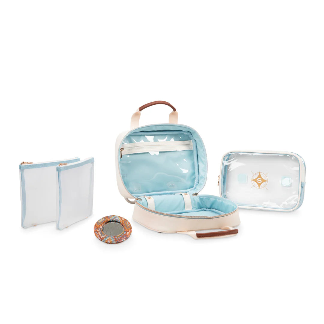 Interior detail view: Stephanie Johnson ML Traveler shown open and empty, highlighting pale blue lining, clear zip pocket, removable clear zip pouch, lift-out clear-topped tray, and round mirror compact in kilim print.