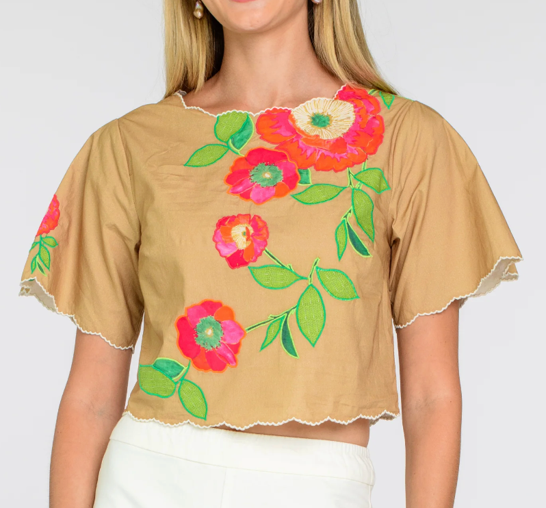 Beige top with colorful floral embroidery on a plain background