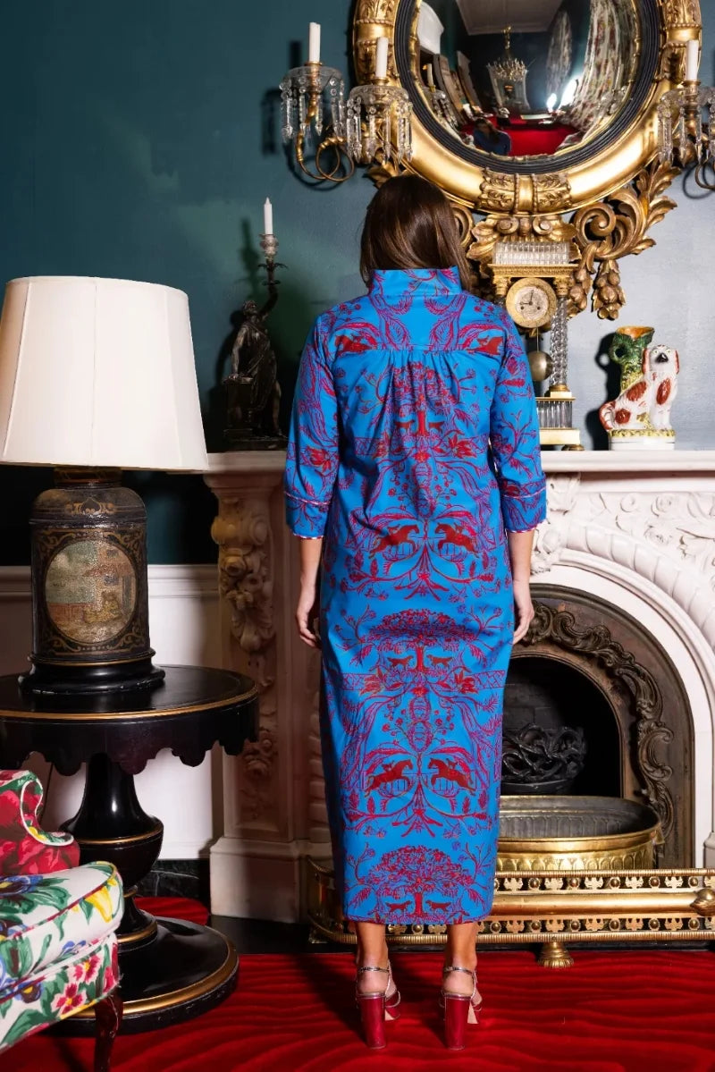 Back view, styled lifestyle: House of MBR Deb Dress Long in Bit and Boll© print shown from behind against a mantel and gilt mirror, highlighting the continuous red equestrian motif down the back, gathered shoulder seam, and tailored cuffs.