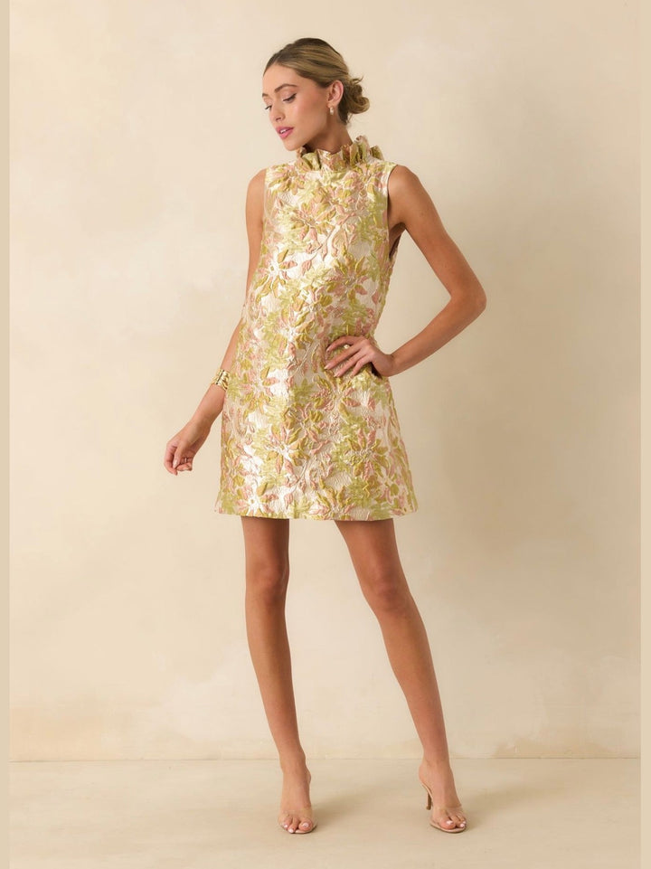 Prosperina Cecily Mini Dress in champagne metallic floral jacquard, sleeveless shift silhouette with ruffled mock neckline, shown on model facing forward.