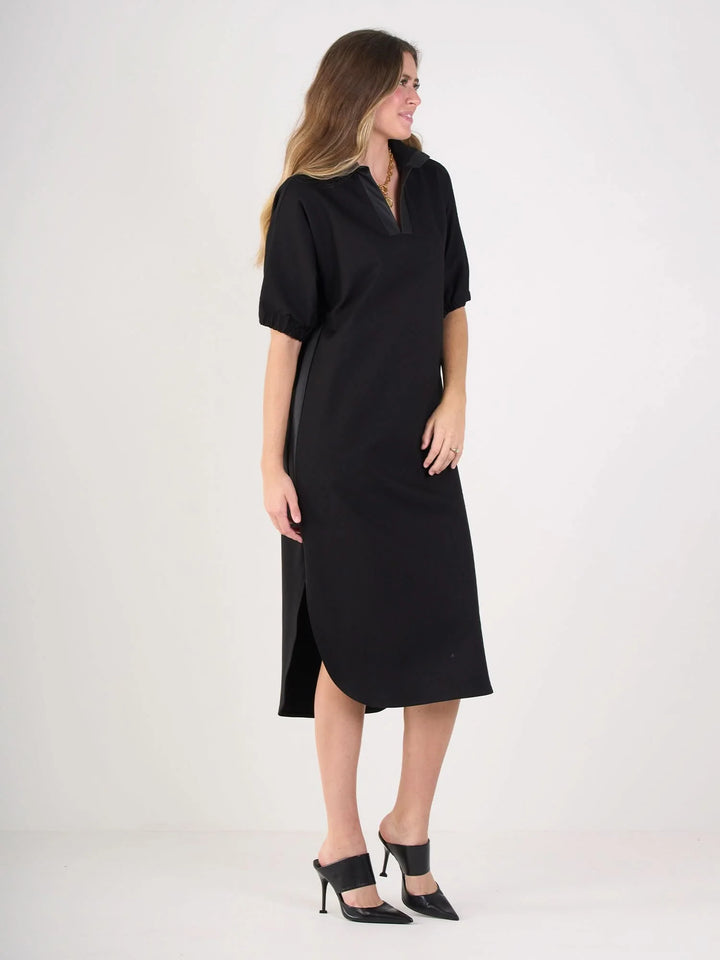 Side of Black ponte caftan with vegan leather tuxedo stripe detail, optional stand collar, and curved tail hem by Emily McCarthy.
