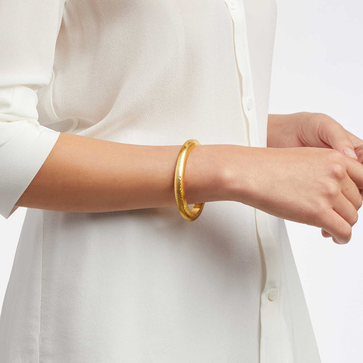 Julie Vos Catalina Hinge Bangle in 24K gold plate — smooth hammered oval band with engraved interior detailing and spring-hinge closure, shown standing upright on white background.