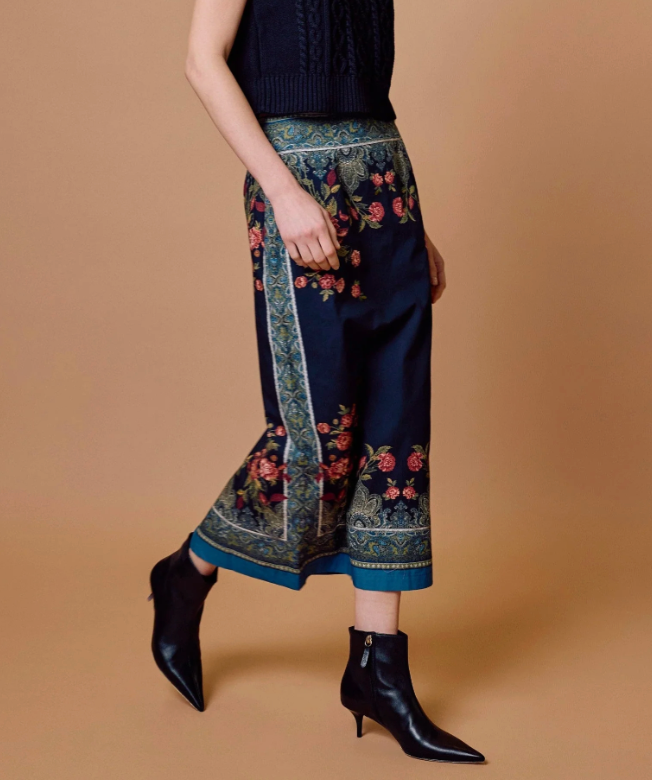 Cleobella Milena Midi Skirt in Eglantine Print, side/walking view, showing placed border print along the hem and leg opening.