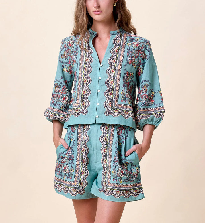 Cleobella Noelle Blouse in teal with multicolor paisley placed print, button-front closure, band collar, and elasticized elbow-length sleeves — front view.