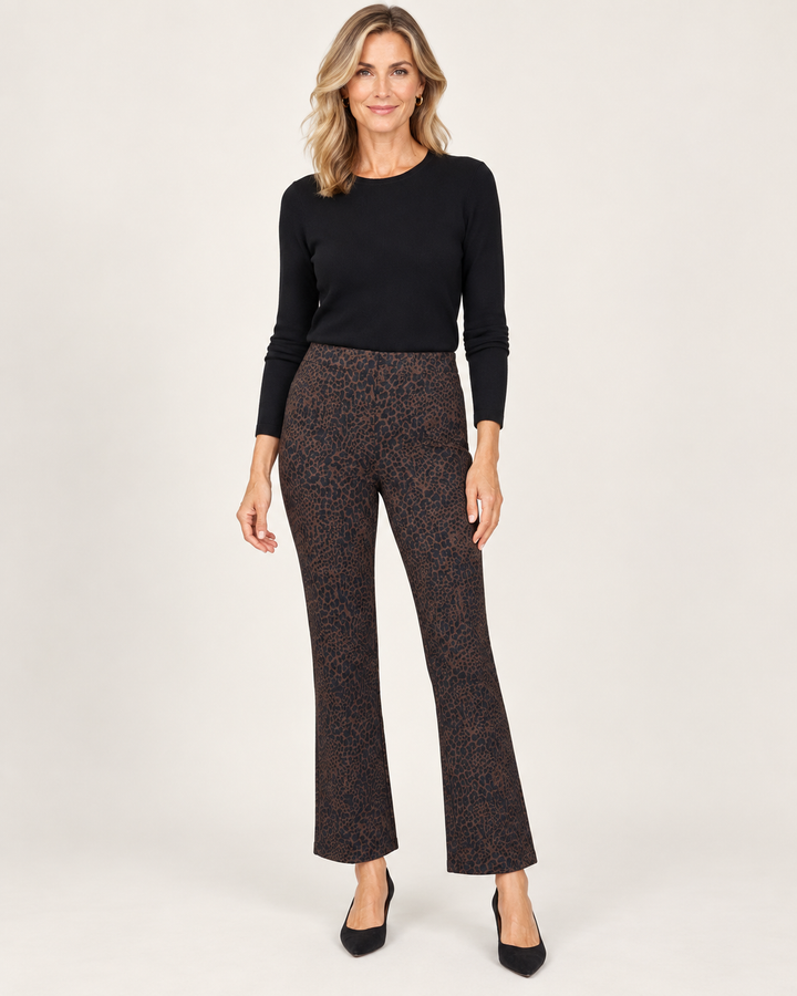 Front view of the same model wearing the leopard-print baby boot pant with a high, fitted waist and slight flare at the ankle, styled with a black top and pumps.