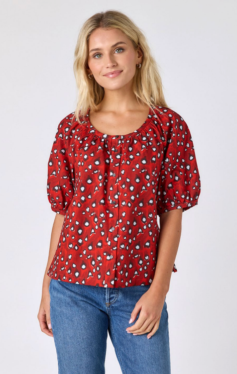 Crosby Perrie Top in brick red and cream abstract print, styled with a gathered scoop neckline, balloon sleeves, and button front, worn with medium-wash denim.