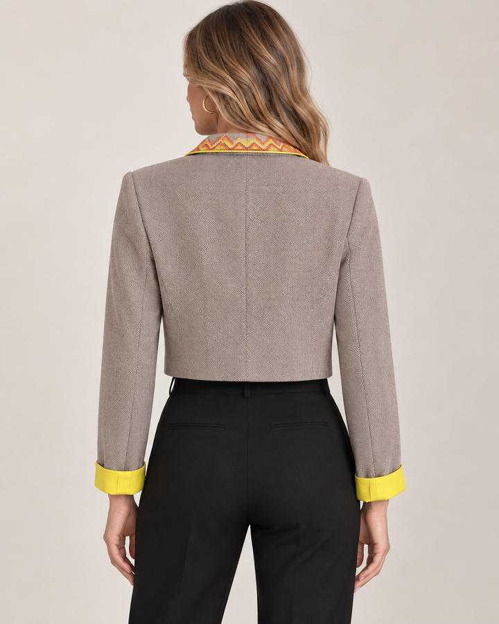 Back view of a model wearing the Eleanor Jacket over a black tank and black trousers, showing the cropped hem and yellow cuff detail.