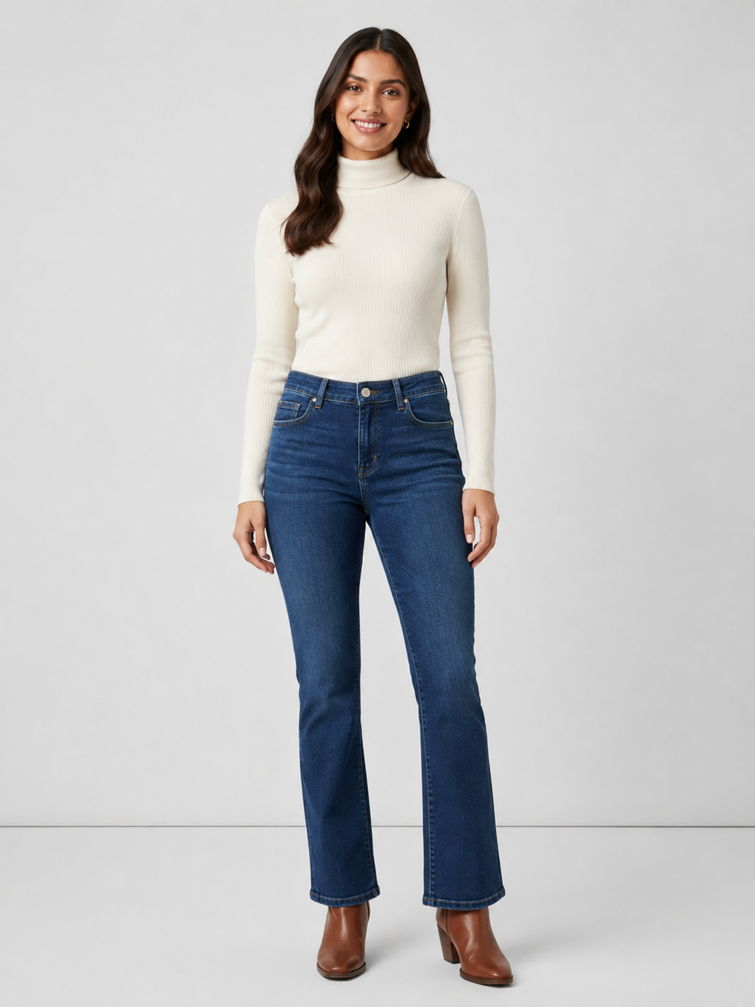 Elliott Lauren Baby Boot Jeans, front view, model wearing dark wash bootcut jeans with ivory turtleneck and brown heeled boots.