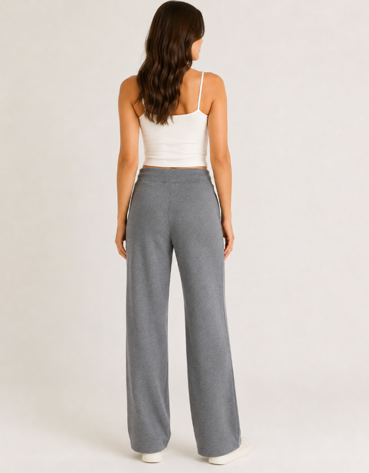A woman shown from the back wearing gray wide-leg knit pants and a white spaghetti-strap crop top, standing against a plain light gray studio background.
