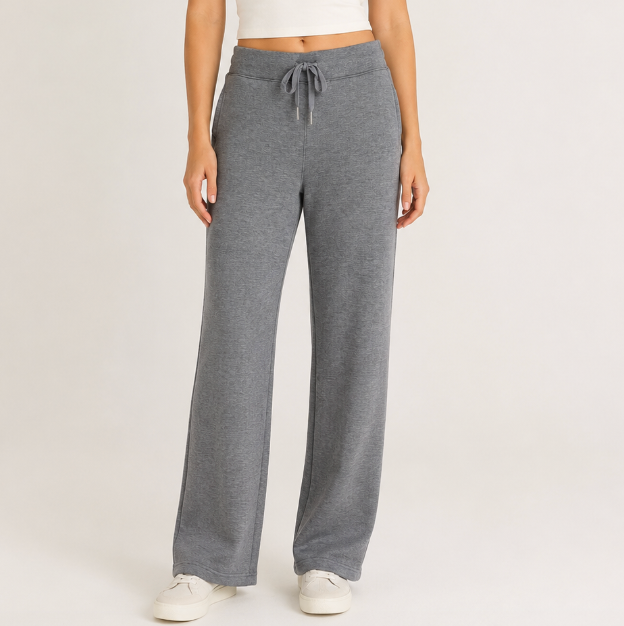 A model wearing a pair of heather gray wide-leg sweatpants with a matching drawstring waistband, paired with a white crop top and white sneakers, against a plain light gray studio background.