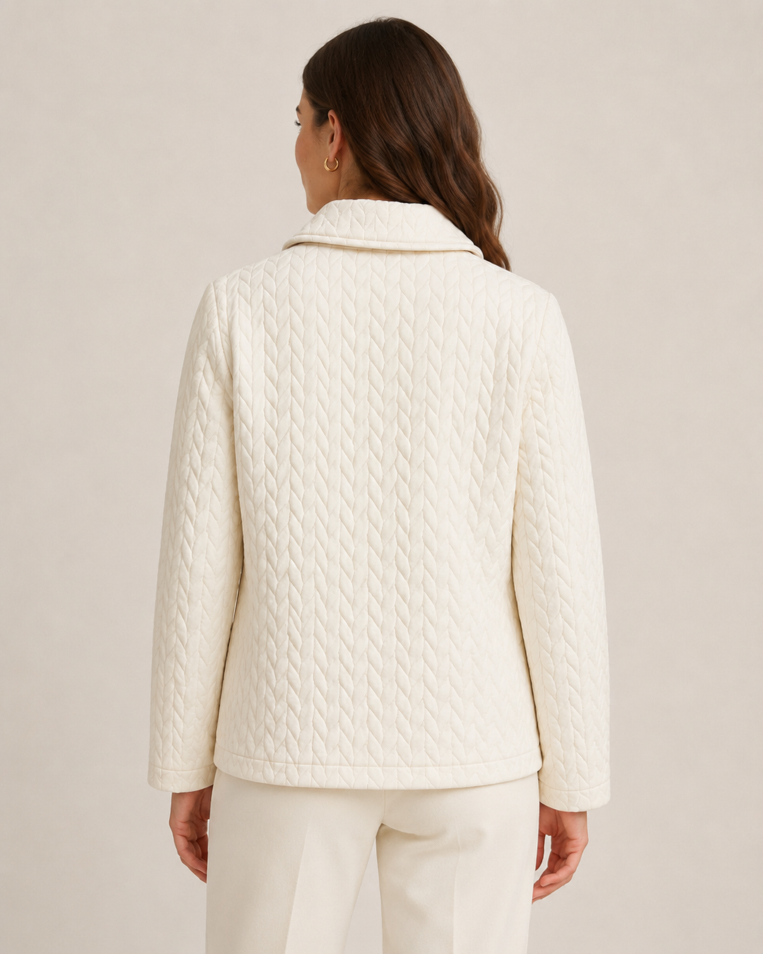 A woman shown from the back wearing a cream-colored quilted jacket and matching cream trousers against a plain beige studio background.