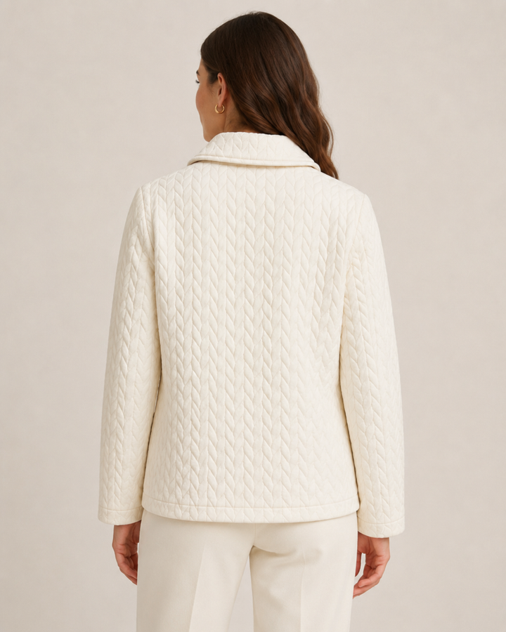 A woman shown from the back wearing a cream-colored quilted jacket and matching cream trousers against a plain beige studio background.