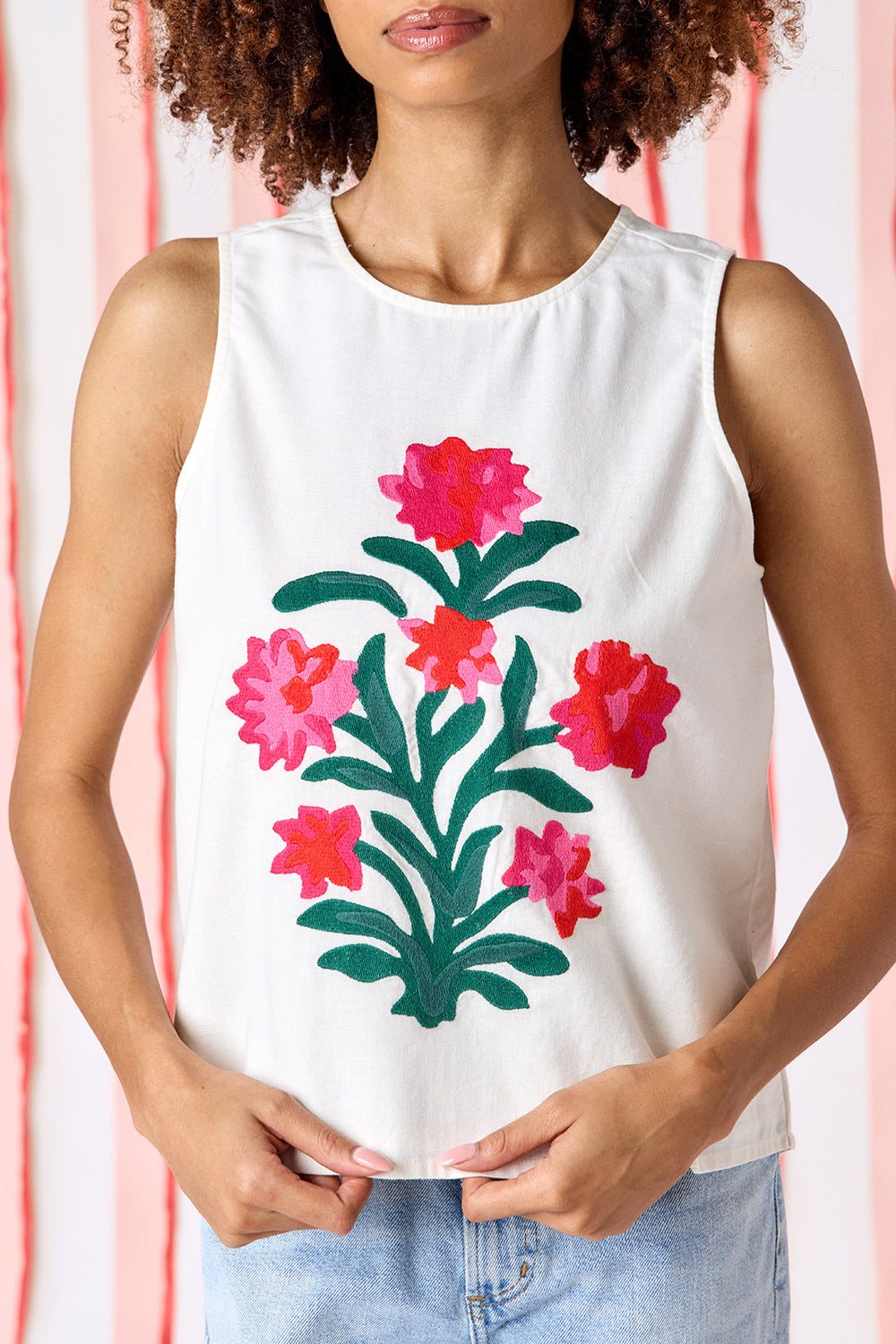 Model wearing Crosby Elly Embroidered Tank Top in ivory styled with light-wash wide-leg jeans. Top features bold botanical floral embroidery centered on front with relaxed boxy fit and crew neckline.