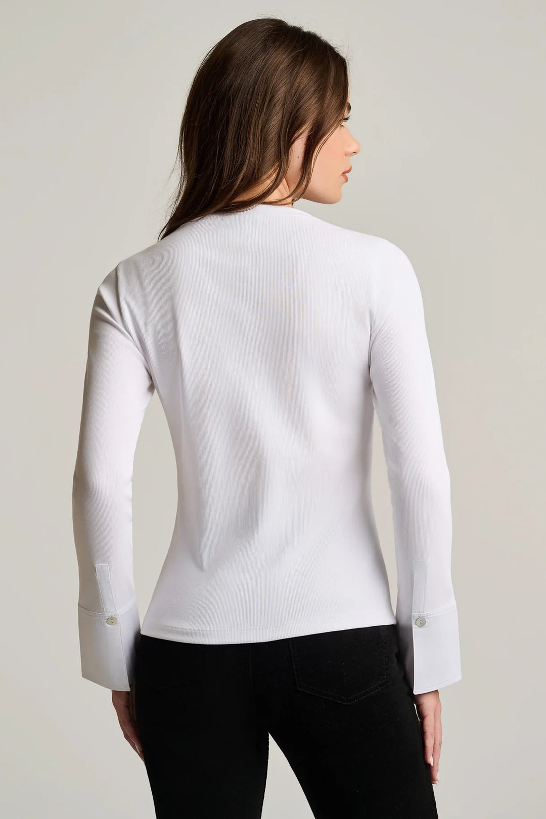 Back view of a woman wearing the Pure Rib Cuff Top in white, showing the fitted silhouette and poplin cuff with button detail on the sleeve.