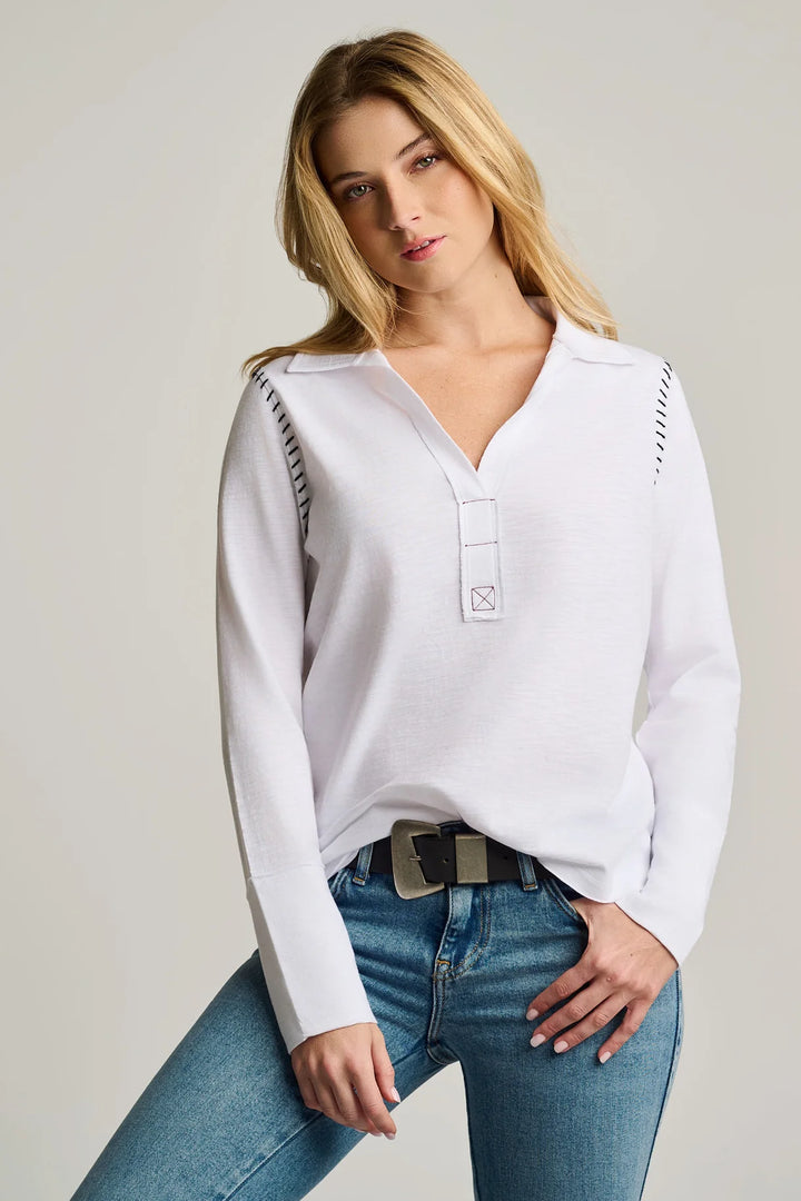 Woman wearing a white long-sleeve shirt and blue jeans on a plain background