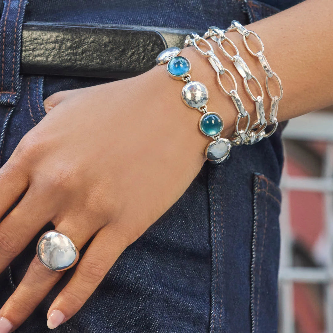 Julie Vos Solara Stone Bracelet in silver plate with cabochon stones alternating with hammered coin links and toggle closure on model with other linked bracelets.