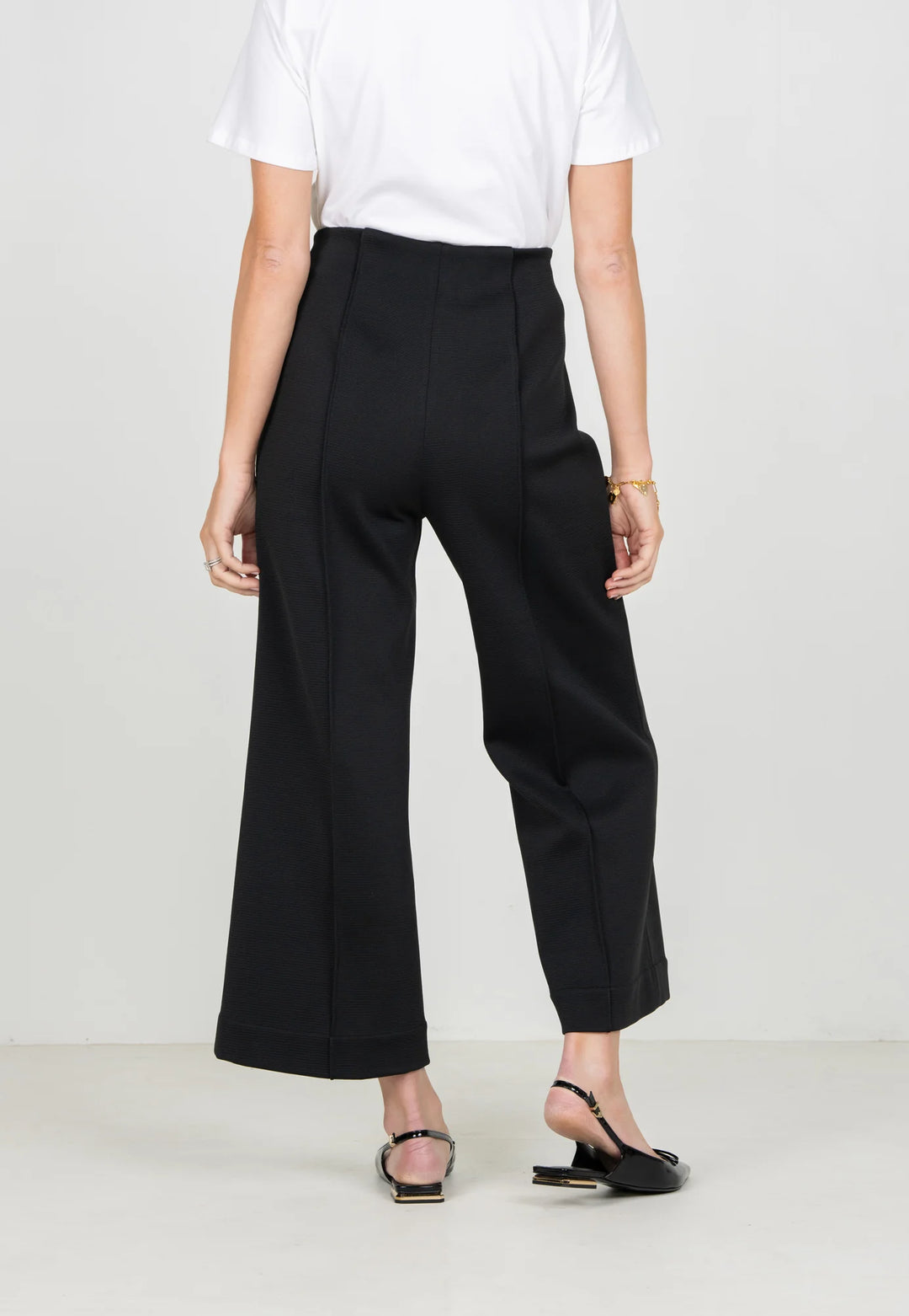 Emily McCarthy Cropped Piper Pant in Black — back detail on-model, showing pin-tuck seam and leg line