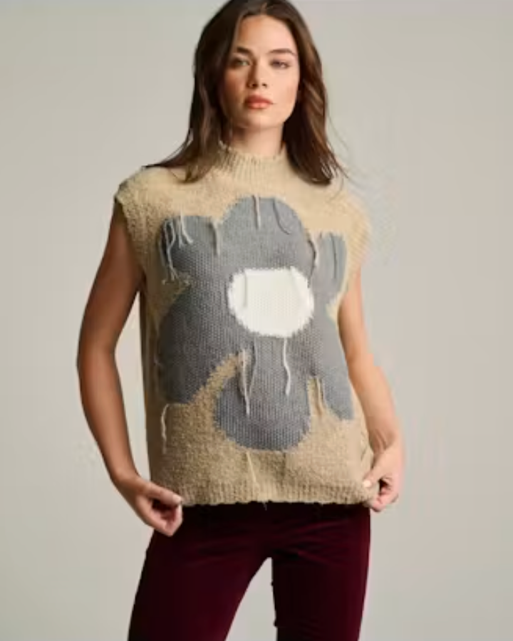 Front view of a woman wearing the Flora Sweater Vest in sand, a sleeveless mock-neck knit vest with an oversized gray and cream floral intarsia design and frayed textural detailing.