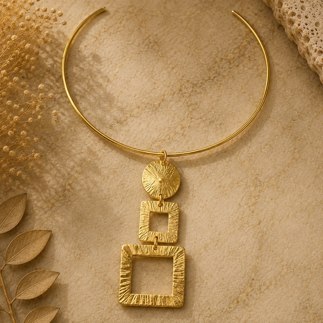 GOMER Gold Geometric Necklace by Ximena Castillo, open collar with three-tier sunburst pendant on natural stone surface