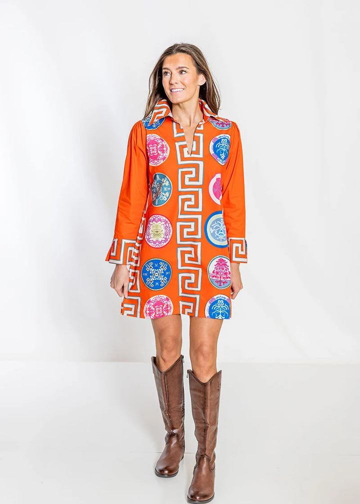 Front view: House of MBR Lana Shirt Dress Short in Greek Revival© print, showing above-the-knee silhouette with orange ground, medallion print, and vertical Greek key border down the center front, styled with brown knee-high boots.