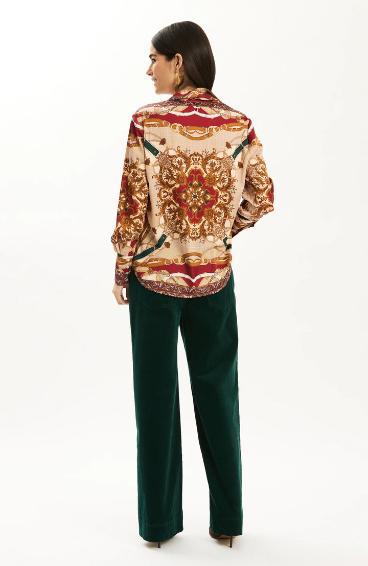 Tyler Boe Chloe Status Charmeuse Blouse, back view on model showing mirrored print, curved shirttail hem, and border-printed cuffs, worn with dark green corduroy wide-leg trousers