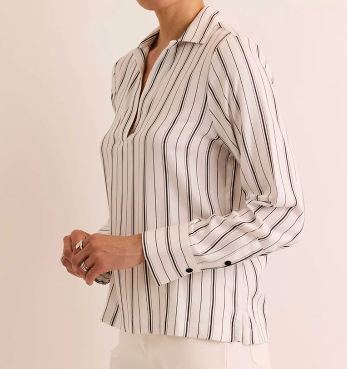Side view of the Hinson Wu Long Sleeve Mona Top in ivory and black stripe, highlighting the relaxed silhouette and side seam vent, paired with white trousers.