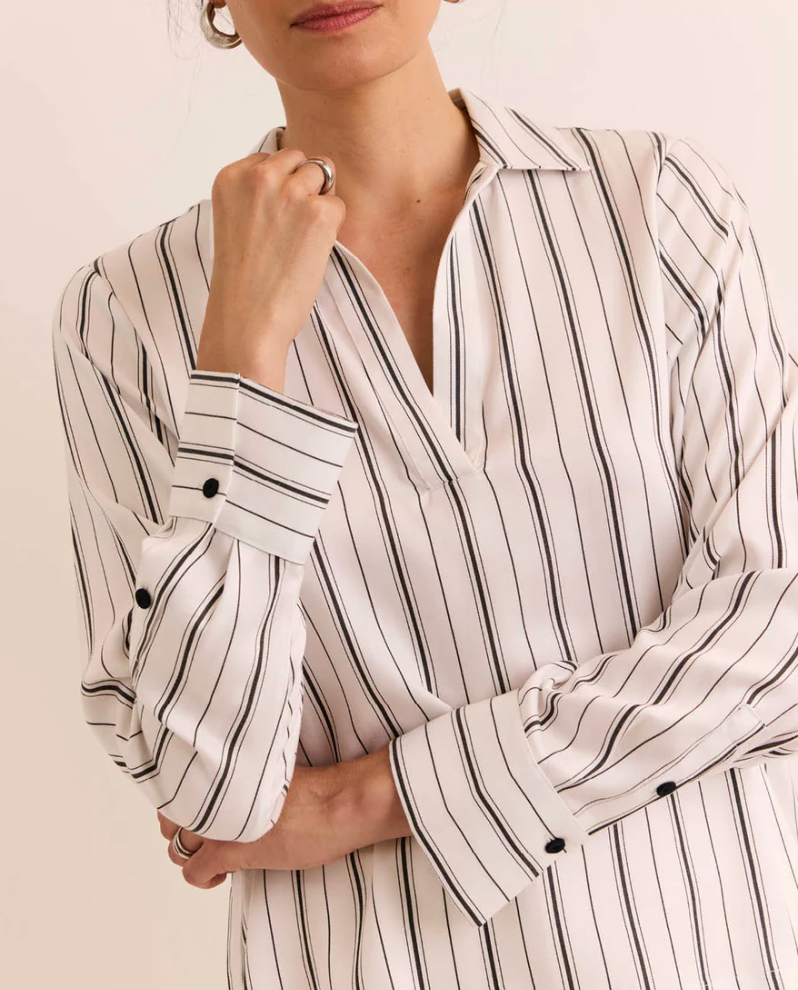 Close-up of the button cuff and collar detail on the Hinson Wu Long Sleeve Mona Top, showing the fine black pinstripe on ivory Tencel fabric and single-button wrist closure.