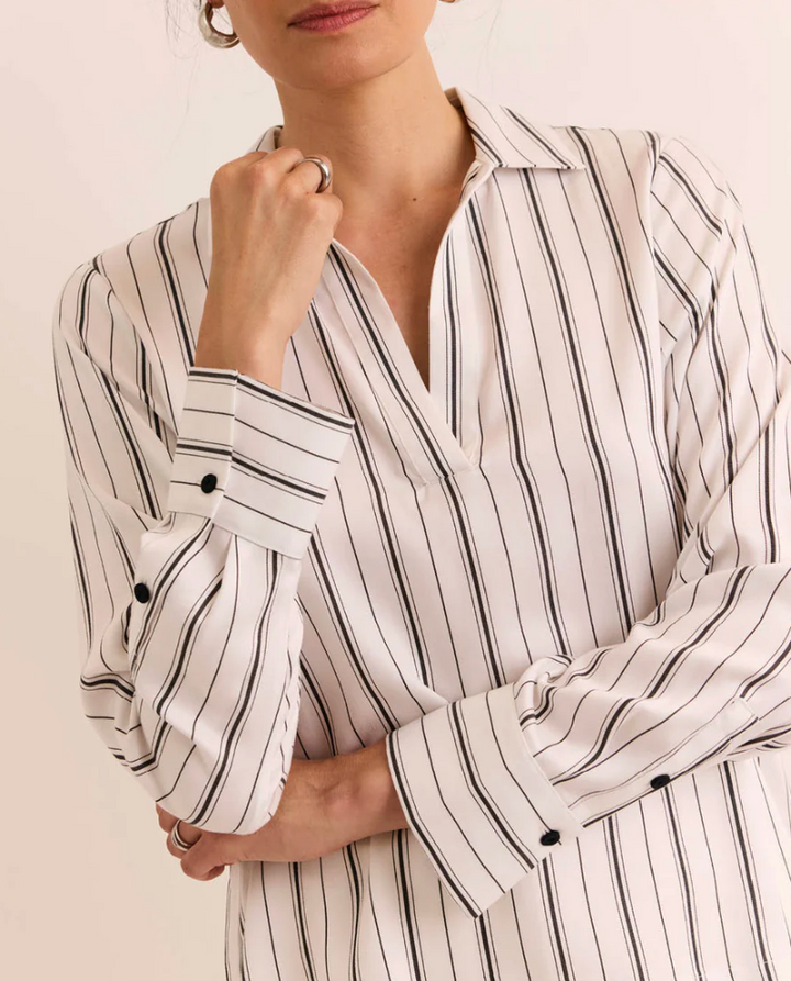 Close-up of the button cuff and collar detail on the Hinson Wu Long Sleeve Mona Top, showing the fine black pinstripe on ivory Tencel fabric and single-button wrist closure.