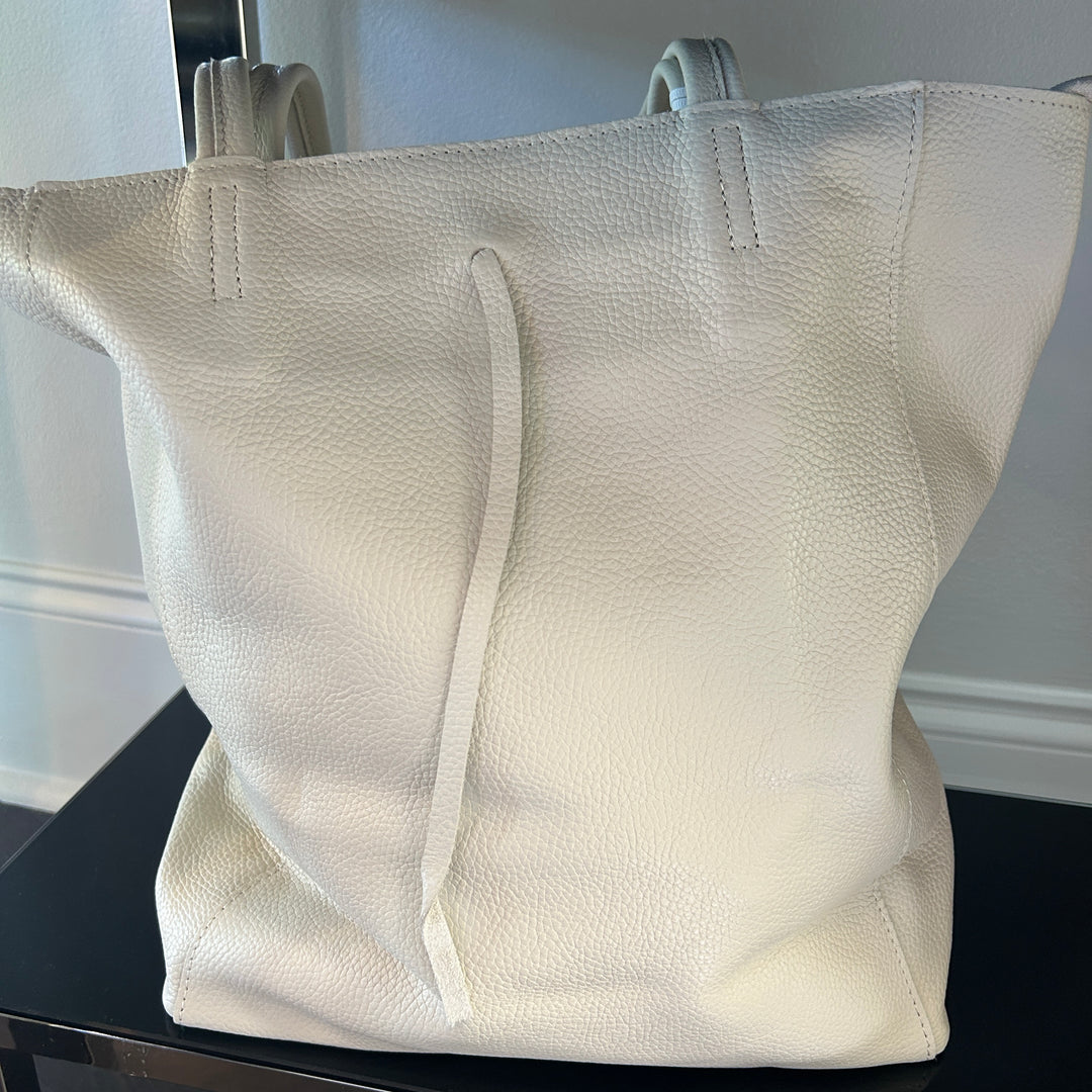 White textured tote bag on a black surface with a neutral background