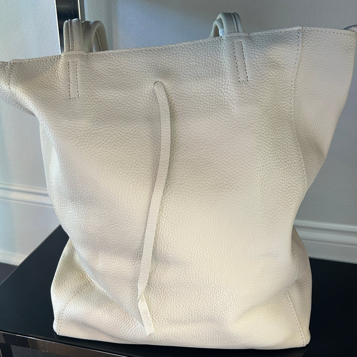 White textured tote bag on a black surface with a neutral background