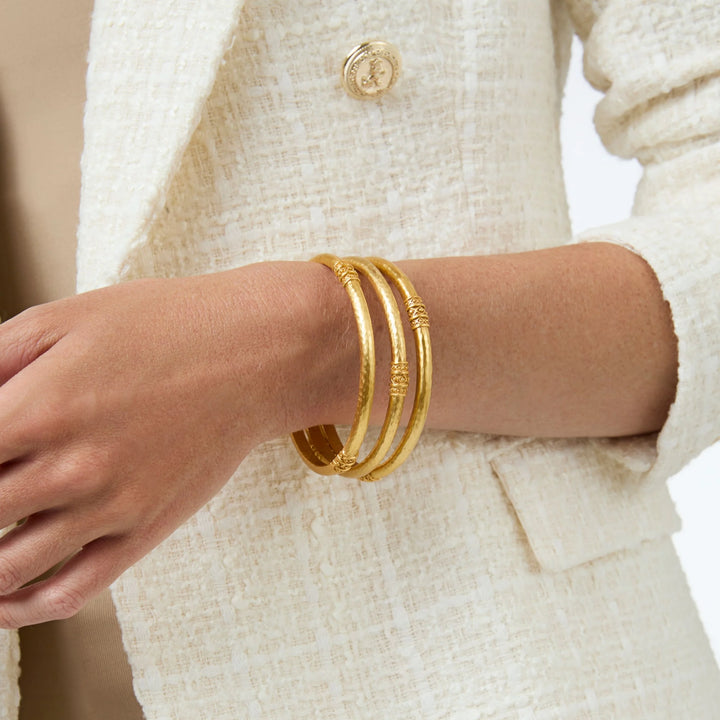 Julie Vos Catalina Bangle in 24K gold plate, shown on wrist — slim hammered band with bead-in-diamond detail.