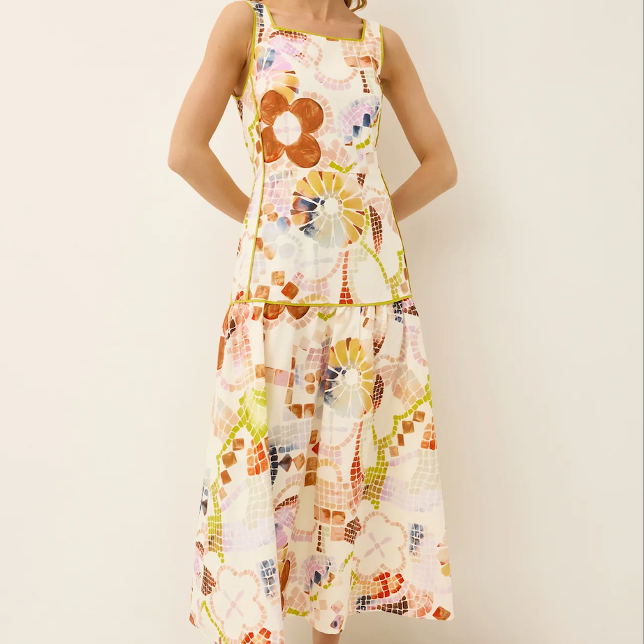 Woman wearing a colorful floral dress on a plain background