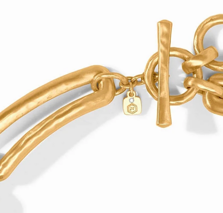 Close-up of the toggle clasp on the Sahara Collar Necklace, showing the hammered gold T-bar closure and Julie Vos hallmark charm with crystal accent.
