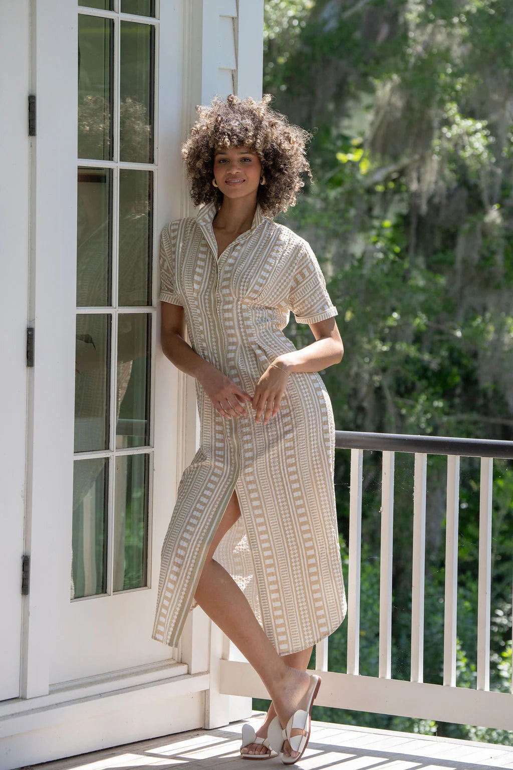 Emily McCarthy Georgia Dress in Piazza Stripe, sand and white geometric stripe cotton midi with stand collar, front button placket, and dolman sleeves, shown with white sandals on model outside.