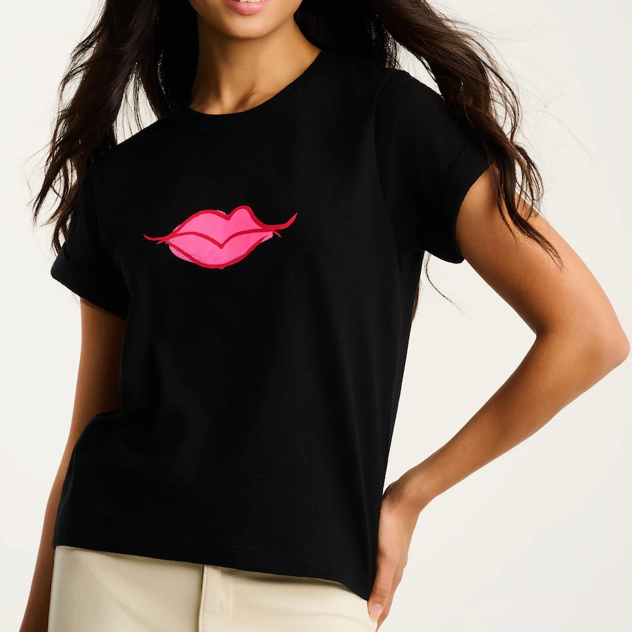 Person wearing a black t-shirt with pink lips design on a plain background