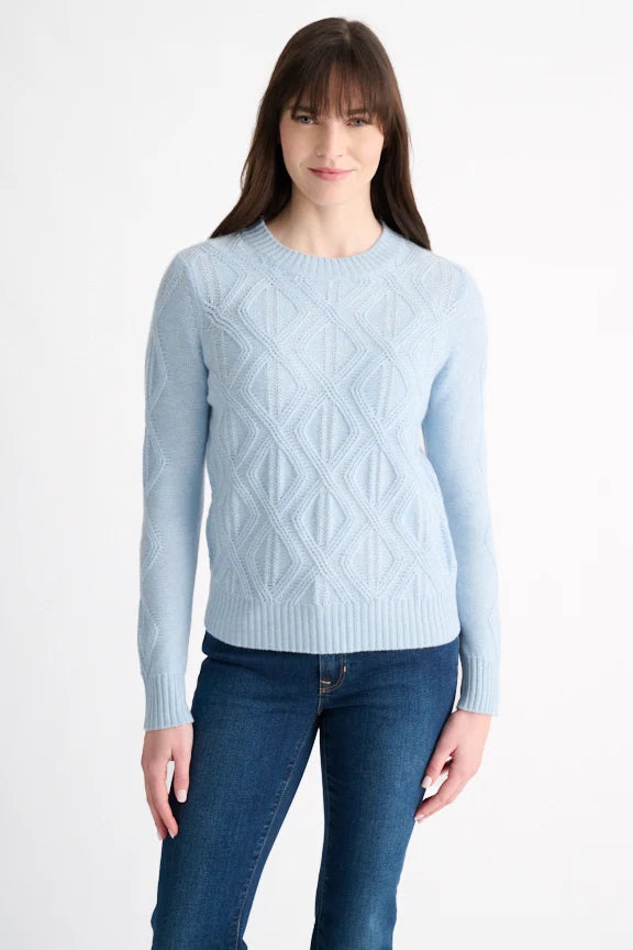 Woman wearing a horizon blue diamond cable knit cashmere crewneck with long sleeves.