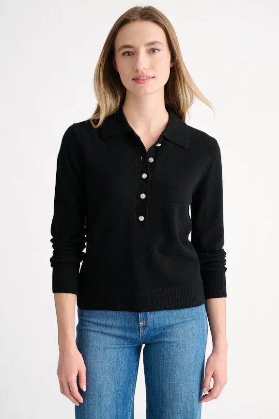 Woman wearing a black cashmere polo sweater with crystal buttons and a collared neckline.